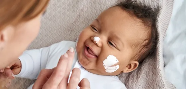 femme qui applique de la crème sur le visage de son bébé