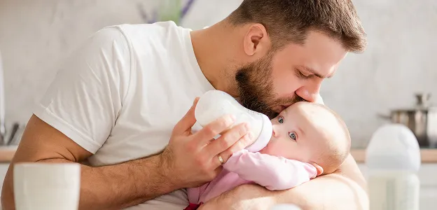 pere entrain de donner le biberon à sa fille