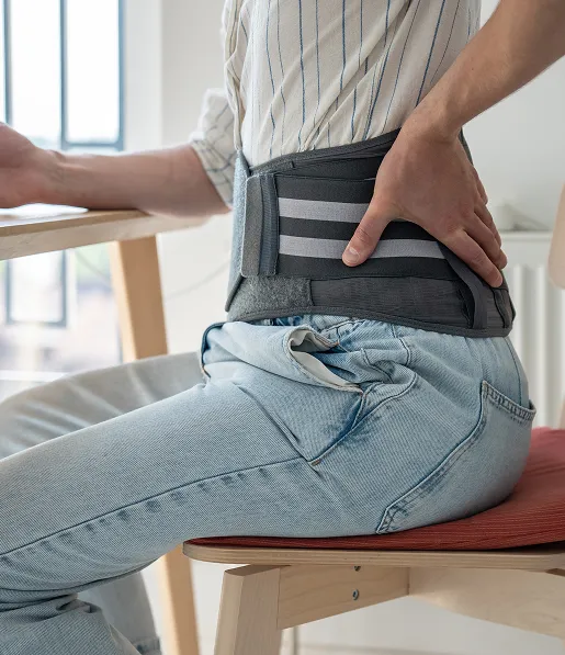 personne assise qui porte une ceinture pour le maintien du dos